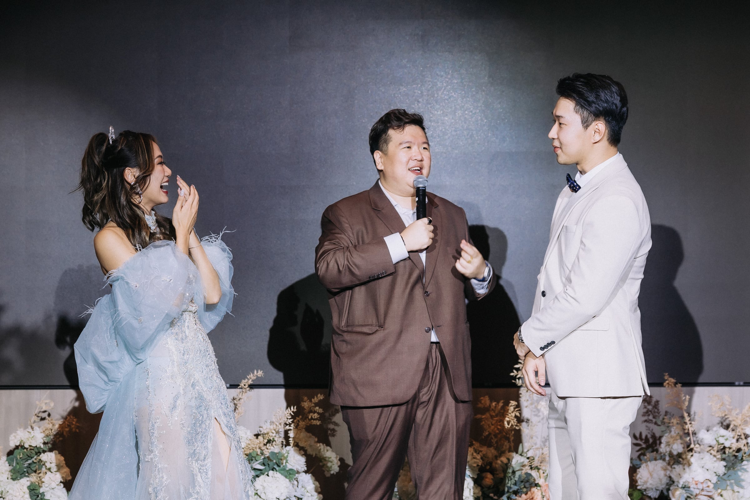 Emcee Dixon hosting between the bride and groom at a Singapore solemnisation